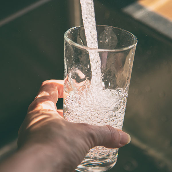 Female pouring fresh drinking tap water into the glass